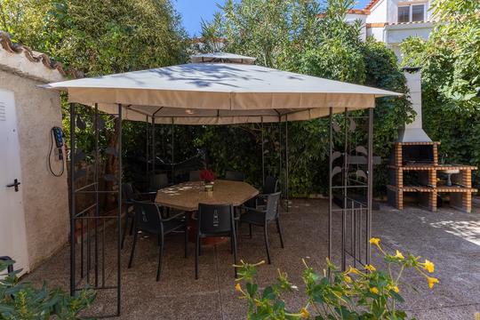 Cenador en jardín delantero con pérgola y barbacoa